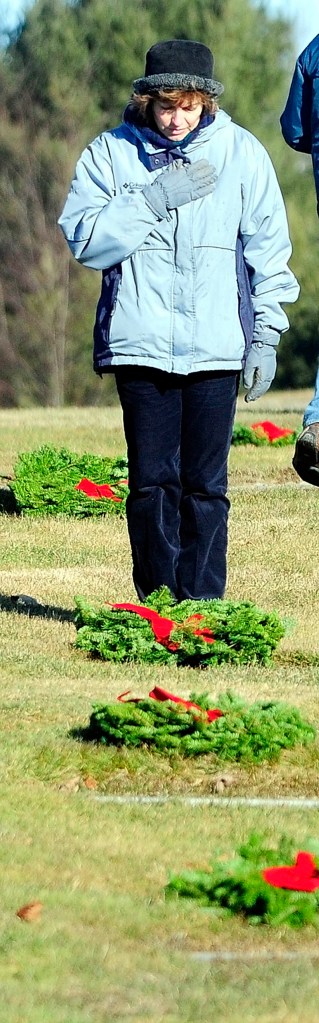 Suzanne Brochu, of Oakland, holds hand over her heart after placing a wreath on a ground-level markers in Maine Veterans Memorial Cemetery on Mount Vernon Road as part of Wreaths Across America events on Saturday. Her son, Army Pfc. Jordan M. Brochu, was killed in Afghanistan in 2009. Dozens of volunteers put 2,704 wreaths, from the Worcester Wreath Company, on veteran's graves at the Togus National Cemetery and the two Maine veterans cemeteries in Augusta, as part of Wreaths Across America events, which included laying of wreaths at Arlington National Cemetery.