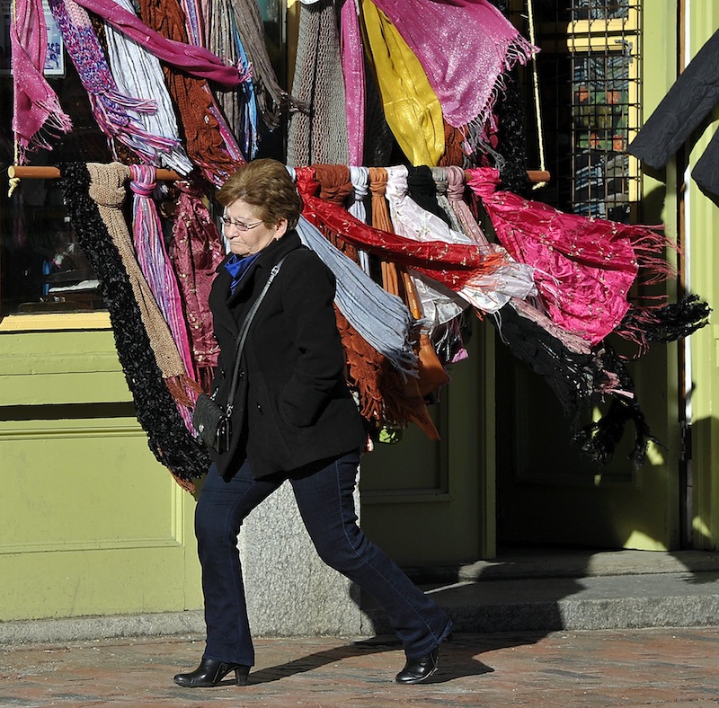 On Thursday, January 31, 2013, the wind blows hard on Fore Street in the Old Port as Pierrette Bolduc from Biddeford passes by a rack of blowing colorful silk and cotton scarves from Indonesia at Siempre Mas.
