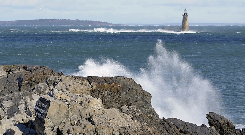 On Thursday, January 31, 2013, the wind blows hard as waves splashing up on the rocks at the Portland Head Light frame Ram Island Ledge Lighthouse and blowing waves.