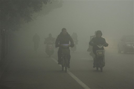 Cyclists travel on the road on a hazy day in Huaibei, in central China's Anhui province on Monday.