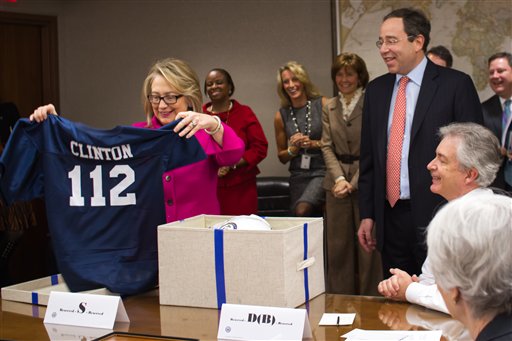 This handout photo provided by the State Department shows Secretary of State Hillary Rodham Clinton holding up a football jersey as she returned to work on Monday after a month-long absence.