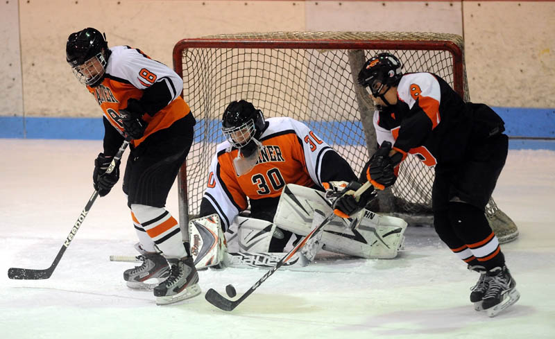 Staff photo by Michael G. Seamans FIND THE PUCK: Skowhegan’s Chase Nelson, right, looks to shoot the puck on Gardiner goalie Brad Moore, center, as teammate Alex Hinckley, left, tries to defend in the second period Saturday night at Sukee Arena in Winslow.
