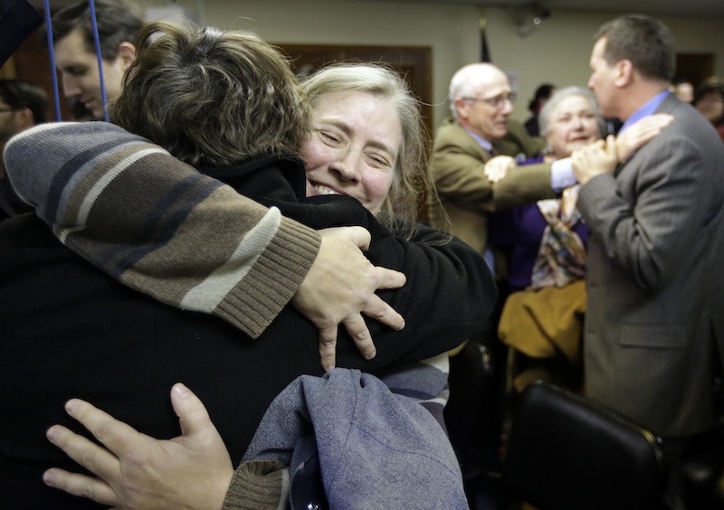 C. Kelly Smith, of Providence, R.I., center, a member of Marriage Equality Rhode Island, hugs fellow member Wendy Becker, left, also of Providence, after a house committee vote on gay marriage at the Statehouse, in Providence, Tuesday, Jan. 22, 2013. The House Judiciary Committee voted unanimously Tuesday to forward legislation to the House that would allow R.I. gay and lesbian couples to marry. (AP Photo/Steven Senne)