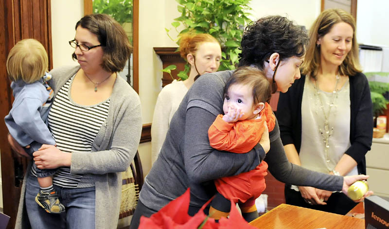 Lilijana Cvetkoska, of Cape Elizabeth, clutches her infant daughter, Olga Malenko, while leaving a can of baby food on the desk of Gov. Paul LePage's receptionist Wednesday during a protest at the State House in Augusta.