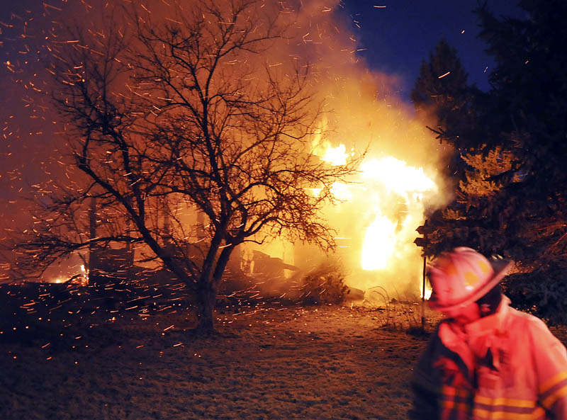 A firefighter walks by the blaze on the Crummett Mountain Road in Somerville Thursday night. Firefighters from several towns were unable to locate the resident of the farmhouse, 92-year-old Cecil Brann.