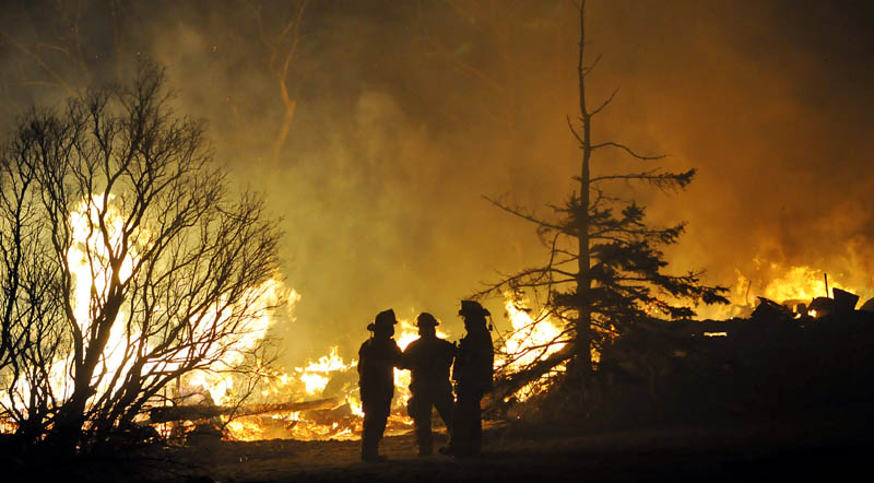 Firefighters confer next to the remains of a barn that burned Thursday on the Crummett Mountain Road in Somerville. Firefighters from several towns were attempting to locate the resident of the farmhouse, 92-year-old Cecil Brann, but were hampered in their efforts by severe cold temperatures.