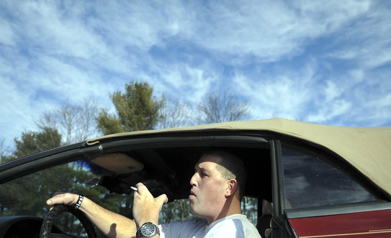 George Speck, of Augusta, smokes a cigarette Monday, in his car at the University of Maine in Augusta. A new policy at the school prohibits the use of tobacco products, except in private vehicles with the windows rolled up.