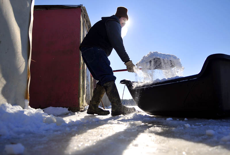 Matt Baker shovels snow up against a smelt shack Wednesday at his family's Pittston business, Baker's Smelt Camps. Baker and his family picked snow up from the river to insulate the exterior of the camps in temperatures, with the wind chill, that were well below zero. "I like the cold," Baker said.
