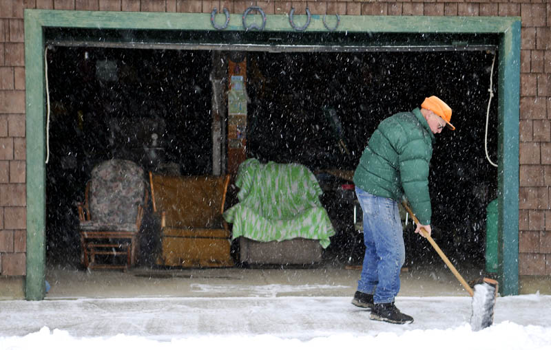 Ernie McPherson battles sleet and snow late afternoon Wednesday while clearing out around his Farmingdale home. McPherson, 85, said he was cutting paths with a broom where his plow couldn't reach, near the barn where he holds court with his son, Ned, and several nephews.