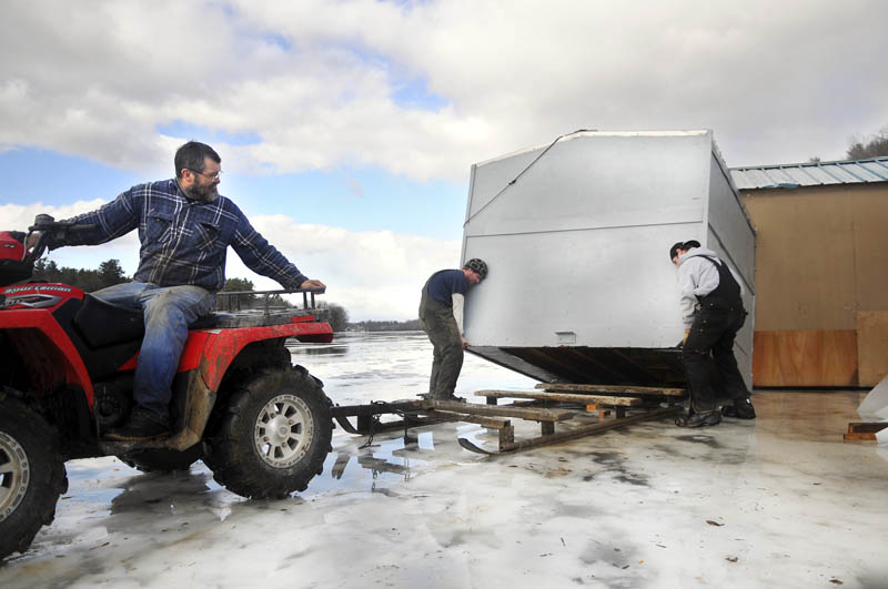 Mike Baker, left, backs under a smelt shack that Brandon Sutherburg, right, and Jeb Baker recovered Thursday on the Kennebec River in Pittston. Shacks at smelt camp operations the length of the river moved across the ice from high wind that gusted up to 50 miles-per-hour. Bakers Smelt Camps had a half dozen get blown away with one still stranded near the center of the river on thin ice, Baker said.