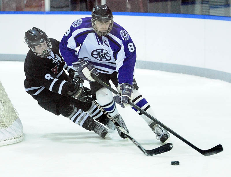 MOVE THE PUCK: MHW’s Matthew Plourde, left, and Waterville senior defenseman Will Bolduc battle for a puck behind the Waterville net during MHW’s 5-4 win Thursday at Colby College in Waterville.