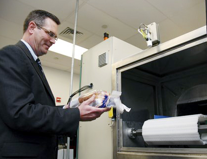 Don Stull, chief executive officer of Microzap Inc., places a loaf of bread inside a patented microwave that kills mold spores.