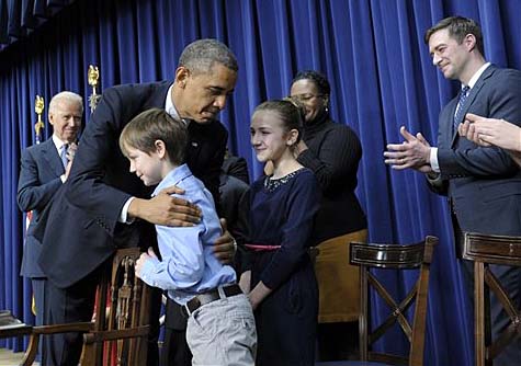 President Barack Obama, accompanied by Vice President Joe Biden, left, hugs 8t-year-old letter writer Grant Fritz during a Wednesday news conference on proposals to reduce gun violence at the White House.