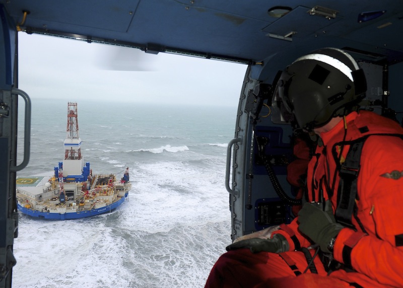 This aerial image provided by the U.S. Coast Guard shows Rear Adm. Thomas Ostebo, Incident Management Team commander, observing the Royal Dutch Shell drilling rig Kulluk aground during an overflight off a small island near Kodiak Island Tuesday Jan. 1, 2013. No leak has been seen from the drilling ship that grounded off the island during a storm, officials said Wednesday, as opponents criticized the growing race to explore the Arctic for energy resources. (AP Photo/U.S. Coast Guard, Sara Francis)