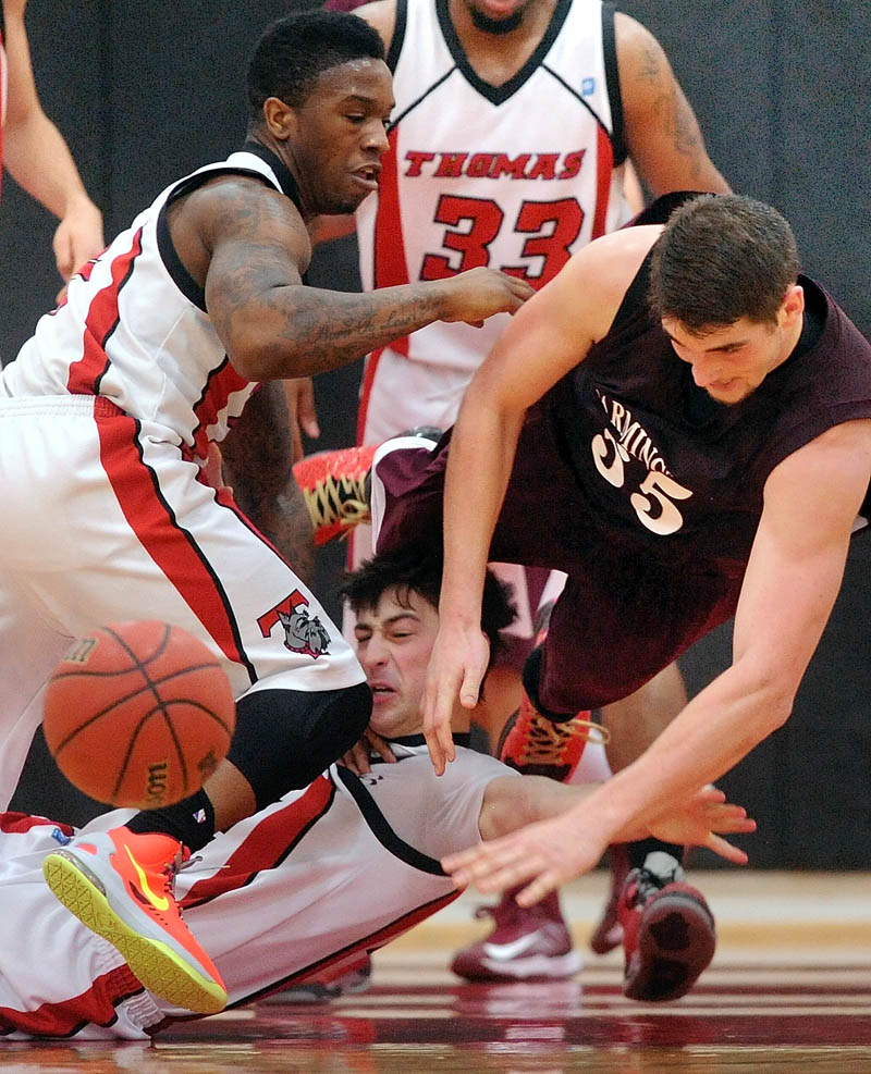LOOK OUT: UMF’s Ben Johnson,right, dives over Thomas College’s Jordan Hoyt, center, in the second half in Waterville Saturday. Thomas College’s Stanley Greene Jr., left, also pursues the loose ball. Farmington defeated Thomas 94-72.