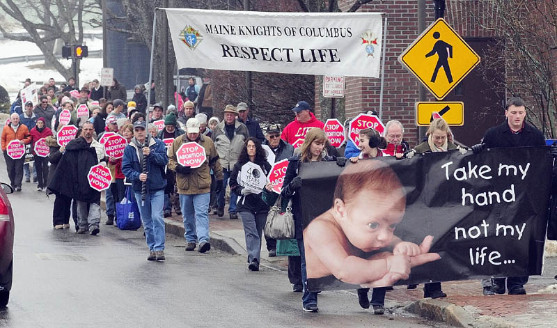 Anti-abortion protesters cross Capitol Street as they march from the St. Michael School gym to the State House during Hands Around the Capitol event on Saturday in Augusta.