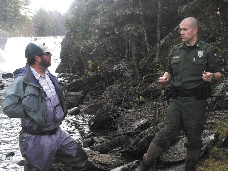 District Game Warden Troy Thibodeau, of Augusta, confers with fly fisherman Ryan Cote, of Monmouth, beneath Grand Falls on the Dead River in an unorganized township in Somerset County. Thibodeau is featured in the television series "North Woods Law."