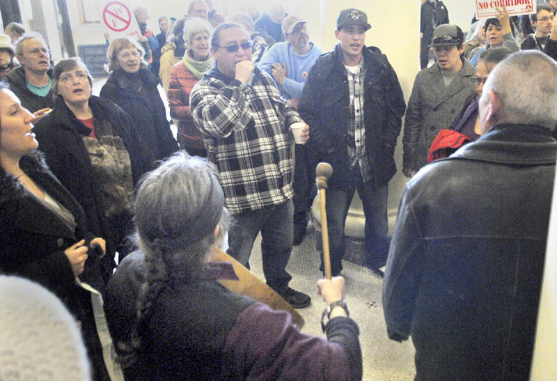 Crow Suncloud, bottom left, plays drum leading a group singing Wabanaki Confederacy songs on Tuesday in the State House's Hall of Flags in Augusta.