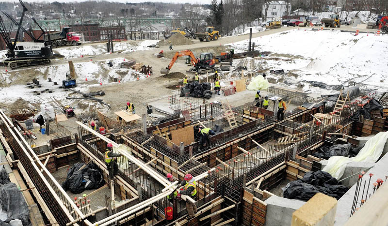 Workers build concrete forms in the foreground as pile driving continues on Tuesday at construction site for the Kennebec County court houses.