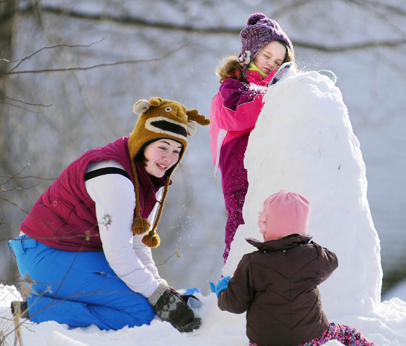 Babysitter Alyssa Withee, 21, left, helps Flannery Brady, seated, age 2, and Laila Brady build a snowman on Saturday outside their Hallowell home.