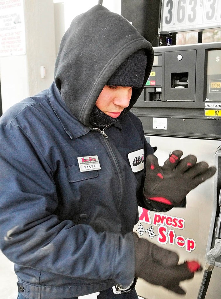 After putting his gloves on, Tyler Kalloch claps his hands to keep warm Tuesday while working the full service gas pumps at the J&S Oil Xpress Stop Convenience Store in Farmingdale. Kalloch said it helps to dress in several layers and to keep moving while working outside on cold mornings - such as the ones this week when the temperature dropped into the single digits.