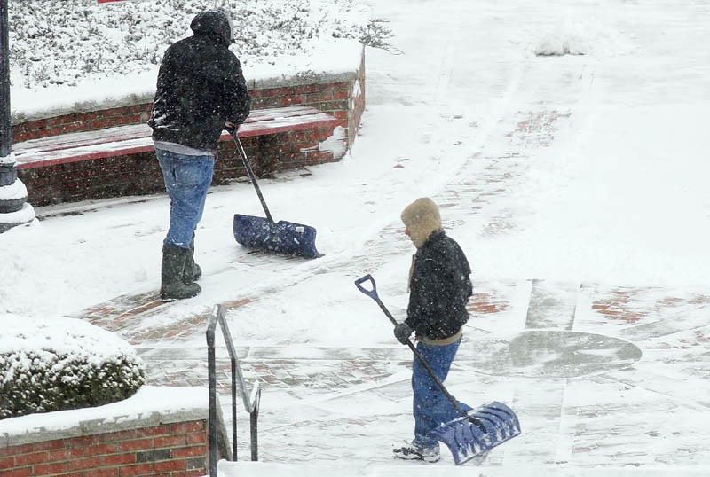 Workers shovels snow on Wednesday Jan. 16, 2013 in front of Key Plaza in downtown Augusta.