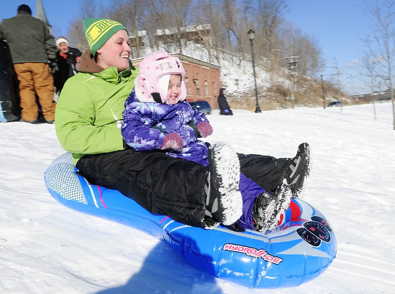Kelsey Morin, left, and her daughter, Hadleigh Morin, 4, both of South China, slide down the Mill Park sledding hill on Tuesday in Augusta. There were several groups of sledders there on the New Year's Day holiday. The sledding hill is near corner of Northern Avenue and Canal Street, between Sand Hill and downtown Augusta.