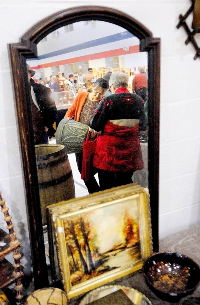Meg Mourey, left, an antiques dealer from Lancaster, N.H., shows a piece of pottery to Miriam Buckley, of Damarine Antiques, on Tuesday at the 22nd annual New Year's Day Antique Sale at the Augusta armory. There were 45 antiques dealers at the show.