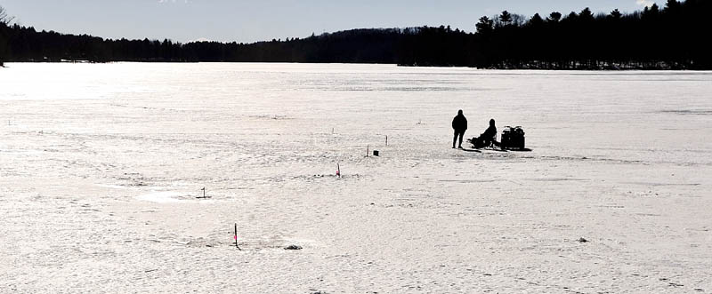 A pair of fisherman wait for a flag to pop up on their ice fishing traps Thursday on Upper Pleasant Pond in Richmond.