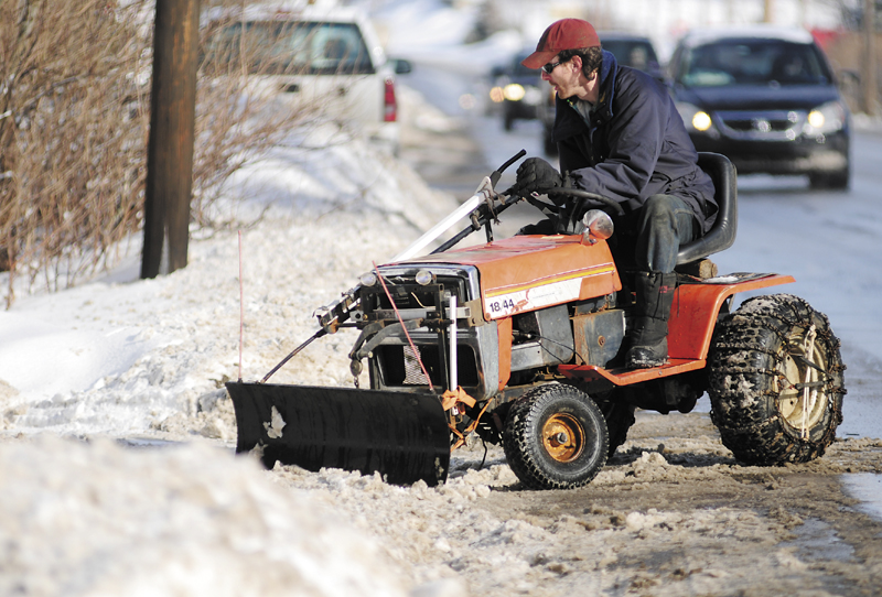 Andrew Nichols clears a driveway with a small plow on his garden tractor on Thursday in Hallowell. The storm the day before had dumped 3 to 4 inches of snow across the area.