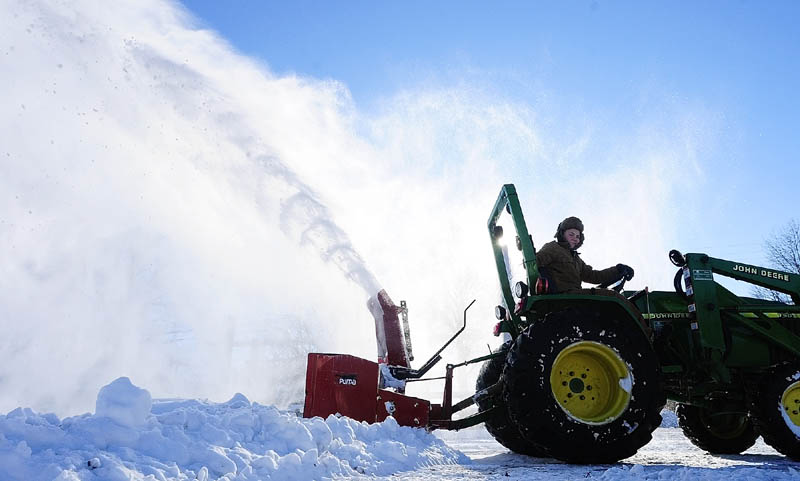 Justin Lord Willett, 12, runs a snowblower on the back of a farm tractor to clear a a work area on Tuesday in Hallowell.