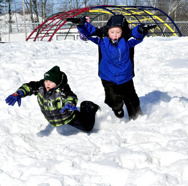 George J. Mitchell School students Jaimin Romagno, left, and Josh Vashon joyfully dive into the snow during recess on Monday in Waterville. School policy allows children to play outdoors if temperatures are 10 degrees F or higher.