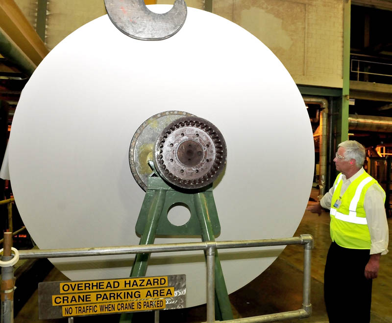U.S. Rep. Mike Michaud examines a huge roll of finished paper made at the Madison Paper Industries mill in Madison, at the start of a statewide tour of mills, on Monday.