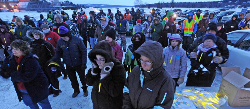 People gather and try to stay warm during a prayer, at the Torch Light Snowmobile Safety Vigil in Rangeley on Friday night.