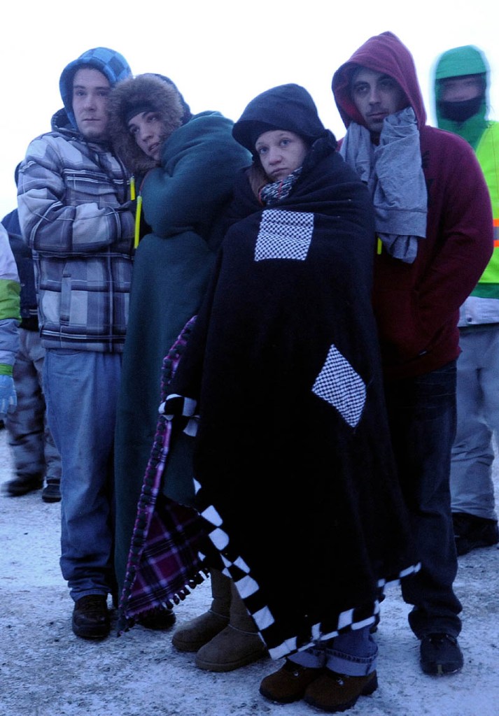 People gather and try to stay warm during a prayer during the Torch Light Snowmobile Safety Vigil in Rangeley on Friday night.