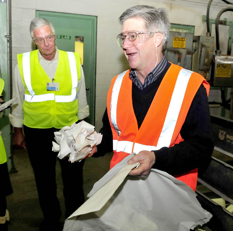 Madison Paper Industries President and CEO Russ Drechsel, right, shows grades of paper from a finished roll made at the Madison mill during a tour for Congressman Mike Michaud, left, on Monday.