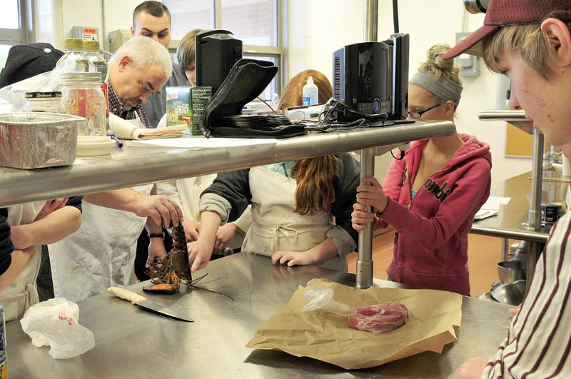 Regional School Unit 9 culinary arts teacher Sean Minear shows students how to prepare a lobster, in a crowded room at Mt. Blue High School Learning Campus in Farmington recently. More space will become available for the program when the three-year expansion project is finished later this year.