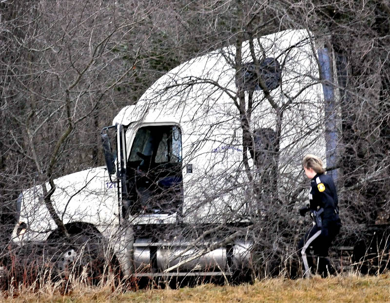 Fairfield police officer Shana Blodgett investigates a tractor trailer truck that went into a wooded section of U.S. Route 201 in Fairfield following a collision with a department cruiser that left officer Bill Beaulieu injured on Thursday.