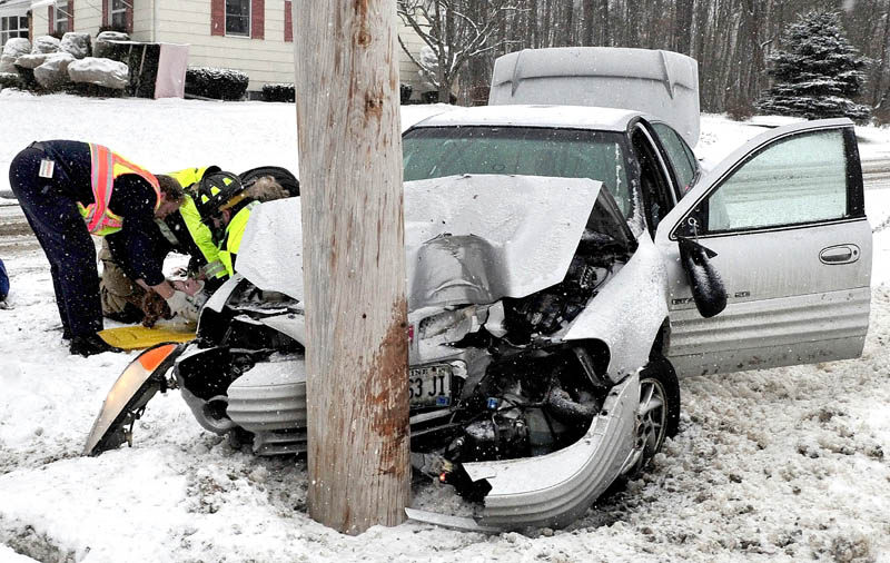 A female occupant of this vehicle is treated by ambulance personnel after the vehicle slid off snow covered Chase Avenue in Waterville and struck a utility pole on Wednesday.