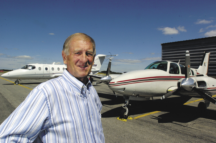 Bill Perry, owner of Maine Instrument Flight at the Augusta State Airport, with a prop plane and a jet.