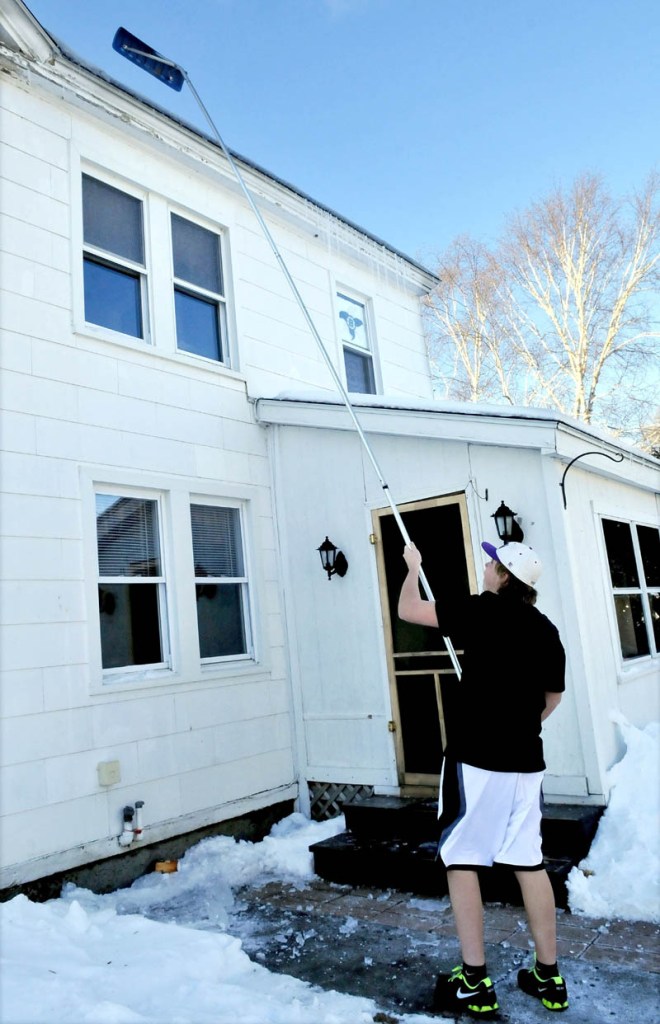 It may have been freezing outside, but not enough for Cameron Aucion to wear long pants while using a roof rake to knock down icicles off a home in Waterville on Wednesday. "I don't think its really cold anyway, " Aucion said.