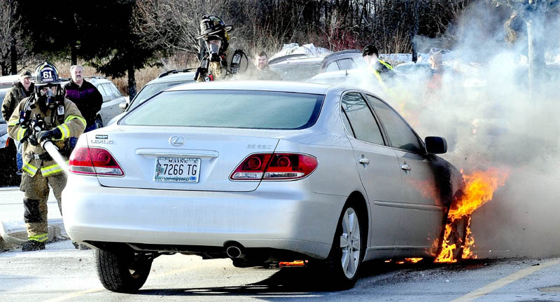 Waterville firefighters extinguish a fire that destroyed a 2005 Lexus sedan parked at Marden's Surplus and Salvage, at 458 Kennedy Memorial Drive in Waterville, on Monday. Owner Lucille Roberge of Waterville said the car, which she recently purchased, was insured. "I came out of the store from shopping and said to myself that someone's car was on fire, before I realized it was mine," Roberge said. "I loved that car."