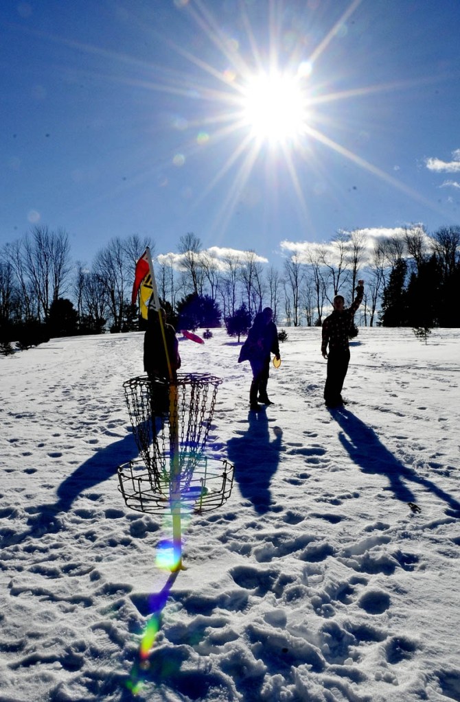 Staff photo by David Leaming JANUARY THAW: Dalton McGovern, right, throws his hand in the air in hopeful anticipation as the disc he threw heads for the basket while playing disc golf at the Quaker Hill Farm in Fairfield on an unseasonably warm day on Thursday, Jan. 10, 2013. Also playing and enjoying the sunny day are Josh Newhall, left, and his cousin Sean Newhall.