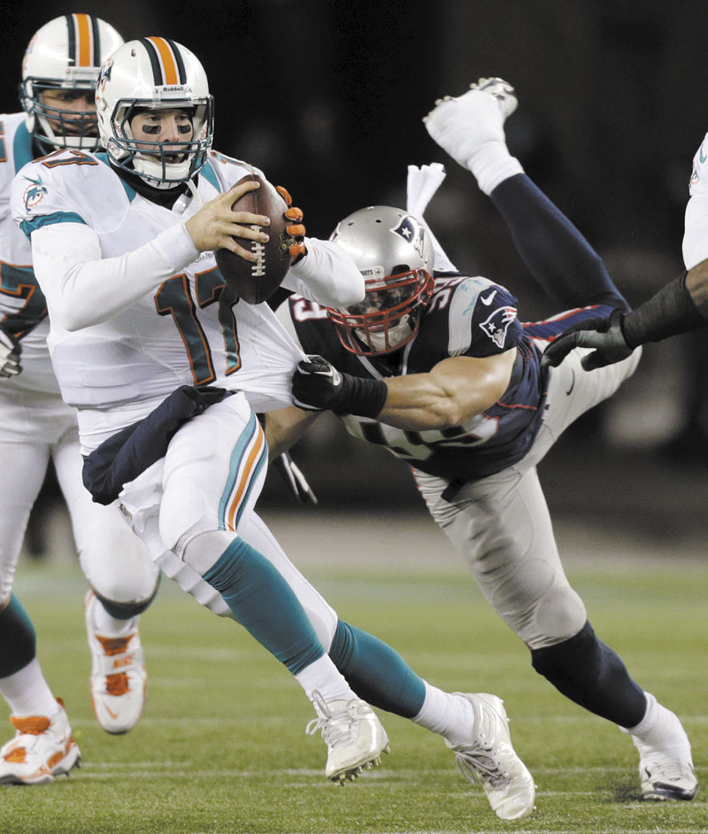 BIG EFFORT: Defensive end Trevor Scott (99) tries to tackle Miami Dolphins quarterback Ryan Tannehill (17) during the third quarter of the Patriots’ 28-0 win Sunday in Foxborough, Mass. Gillette Stadium