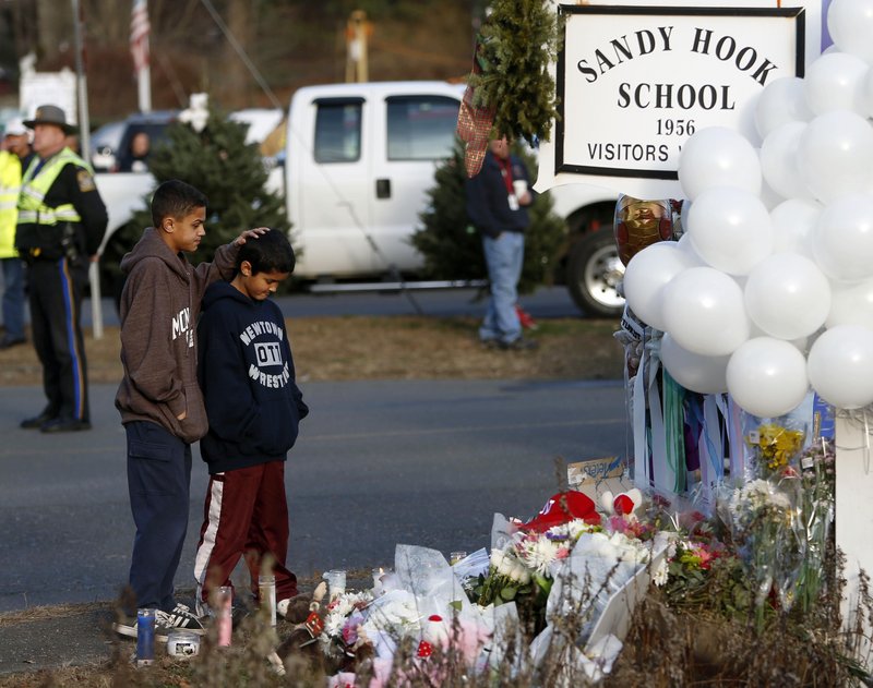 Thomas and Steven Leuci, a pair of 13- and 9-year-old brothers, pay respects at a memorial to victims at Sandy Hook Elementary School last month in Newtown, Conn. The town must decide on what to do with the school – one option is to demolish it and rebuild.