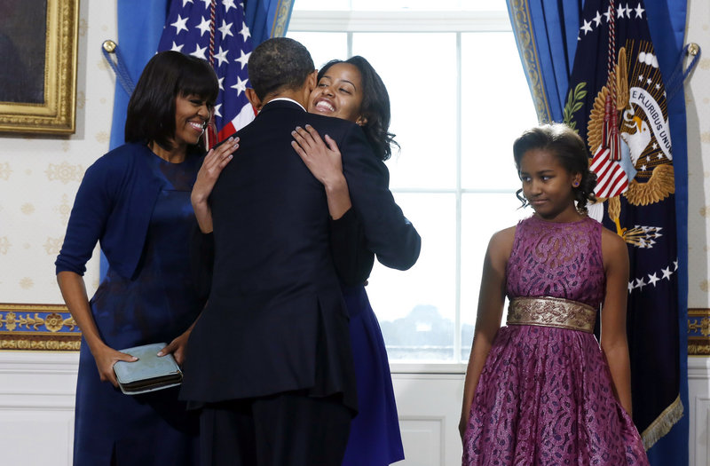 President Obama hugs daughter Malia as first lady Michelle Obama and daughter Sasha watch after Obama was officially sworn into office by Chief Justice John Roberts, not pictured, in the Blue Room of the White House on Sunday.