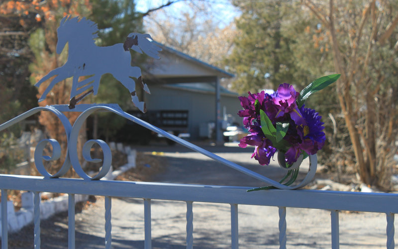 A bouquet adorns the gate Monday at the home where a couple and their three young children were found shot to death south of Albuquerque, N.M., over the weekend.