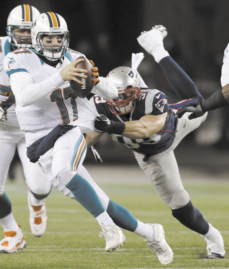 New England Patriots defensive end Trevor Scott (99) tries to tackle Miami Dolphins quarterback Ryan Tannehill (17) earlier this season. Scott will make his playoff debut Sunday. Gillette Stadium