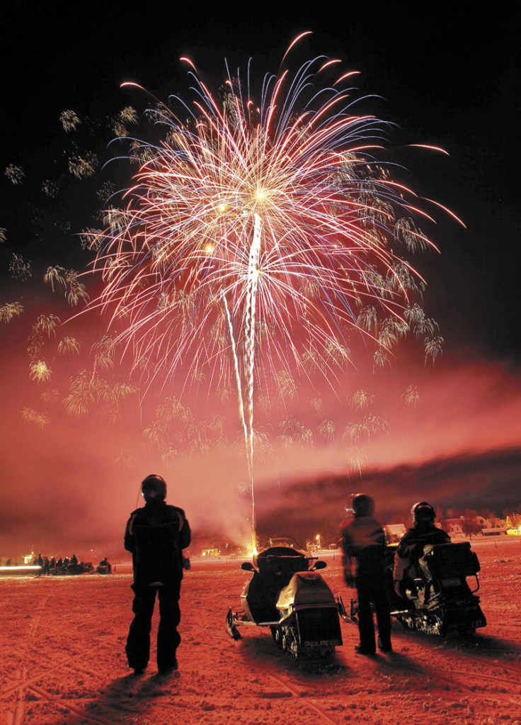 Snowmobilers watch fireworks over Rangeley Lake during the 2011 Snodeo, an annual snowmobiling celebration over the weekend in Rangeley. Some family and friends of three missing snowmobilers, presumed drowned in the lake, object to the festival being celebrated this year, while others believe it's appropriate.