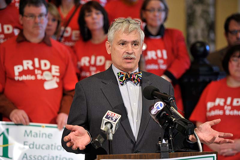 Sen. Tom Saviello, R-Wilton, speaks to the media about his bill to ease limits on what teachers can do to restrain students in the Capitol rotunda on Wednesday, Feb. 20, 2013. Teachers in the background wear matching red "Pride in Public Schools" t-shirts in support of Saviello's bill.